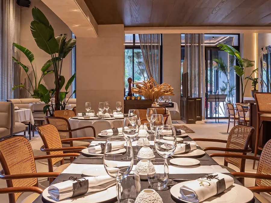Salle du restaurant MB Marrakech, avec des tables dressées et une décoration végétale.